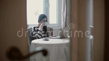 女士使用笔记本电脑，在明亮的餐厅享用早间咖啡。 透过敞开的门观看